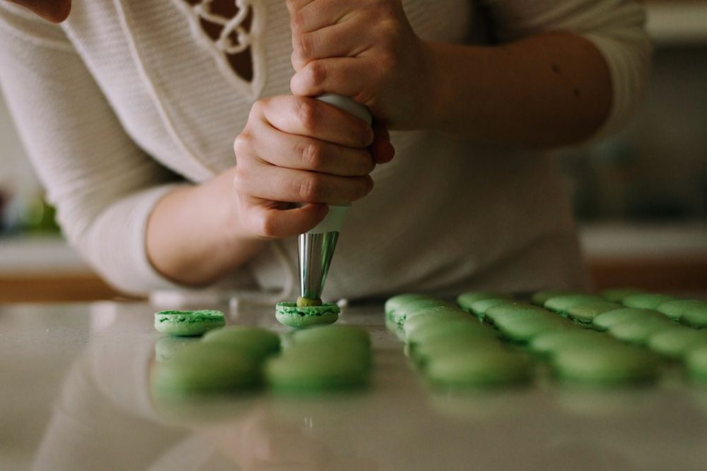Pastelera profesional decorando macarons a mano para la mesa dulce de un evento de Momentos Catering